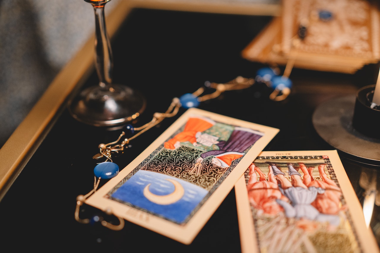 Two tarot cards up right on a table with other miscellaneous items.