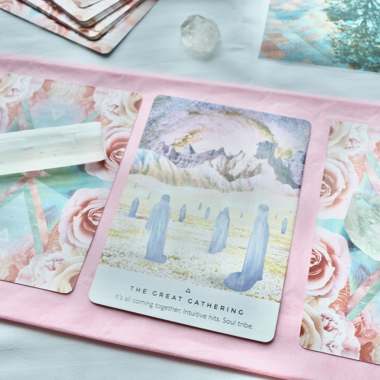 Three tarot cards laid out on a pink piece of cloth with a crystal on the first card. Above the those cards you can see little bit of more cards.