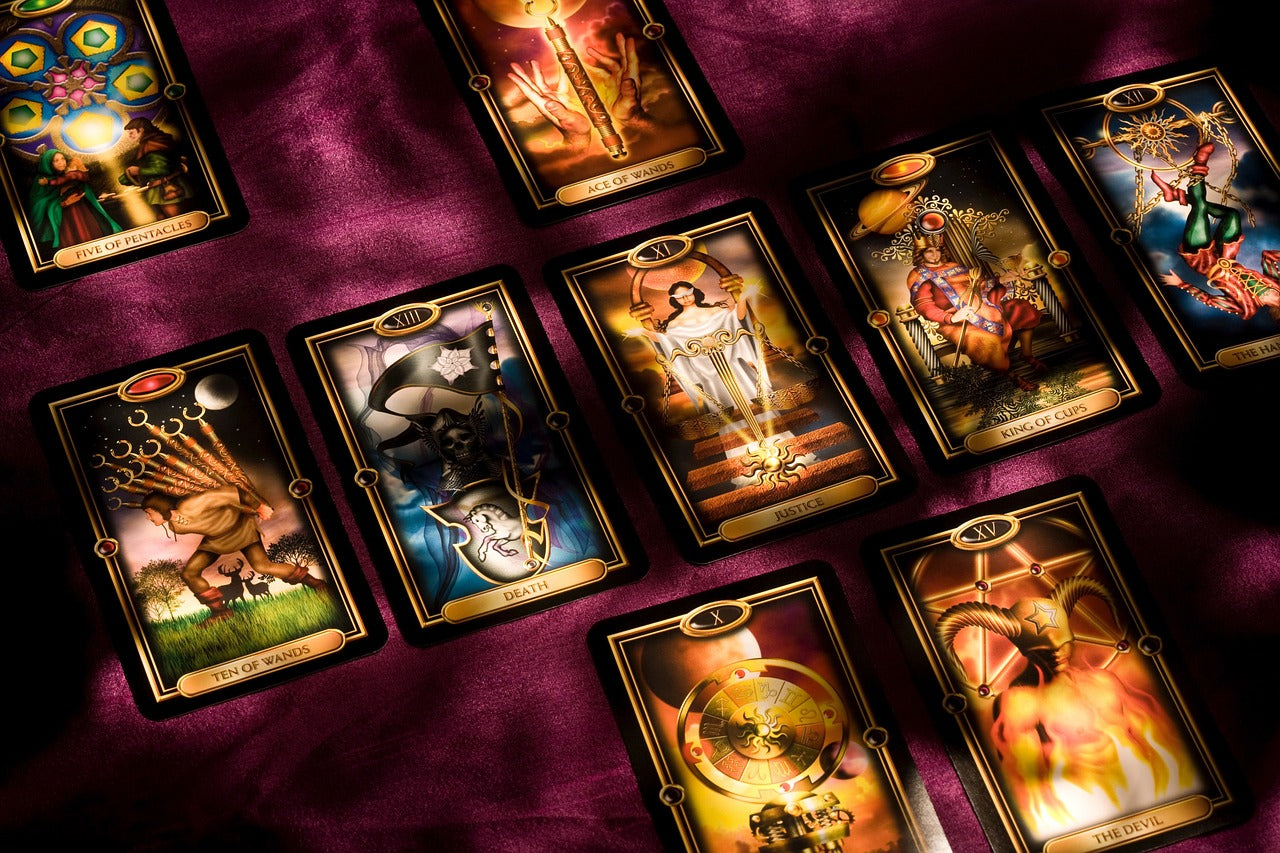 Tarot cards laid out into a tarot spread. In this spread there are three rows, the first row has two cards, the second row has five cards and the third row has two cards. All cards are face up and facing forward.