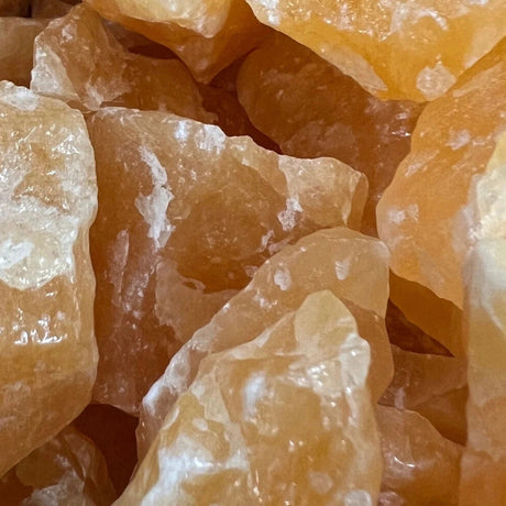 A cluster of raw orange calcite stones with a rough, natural texture.