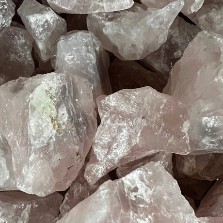 Raw Rose Quartz stones with a rough, natural finish and a pale pink color.