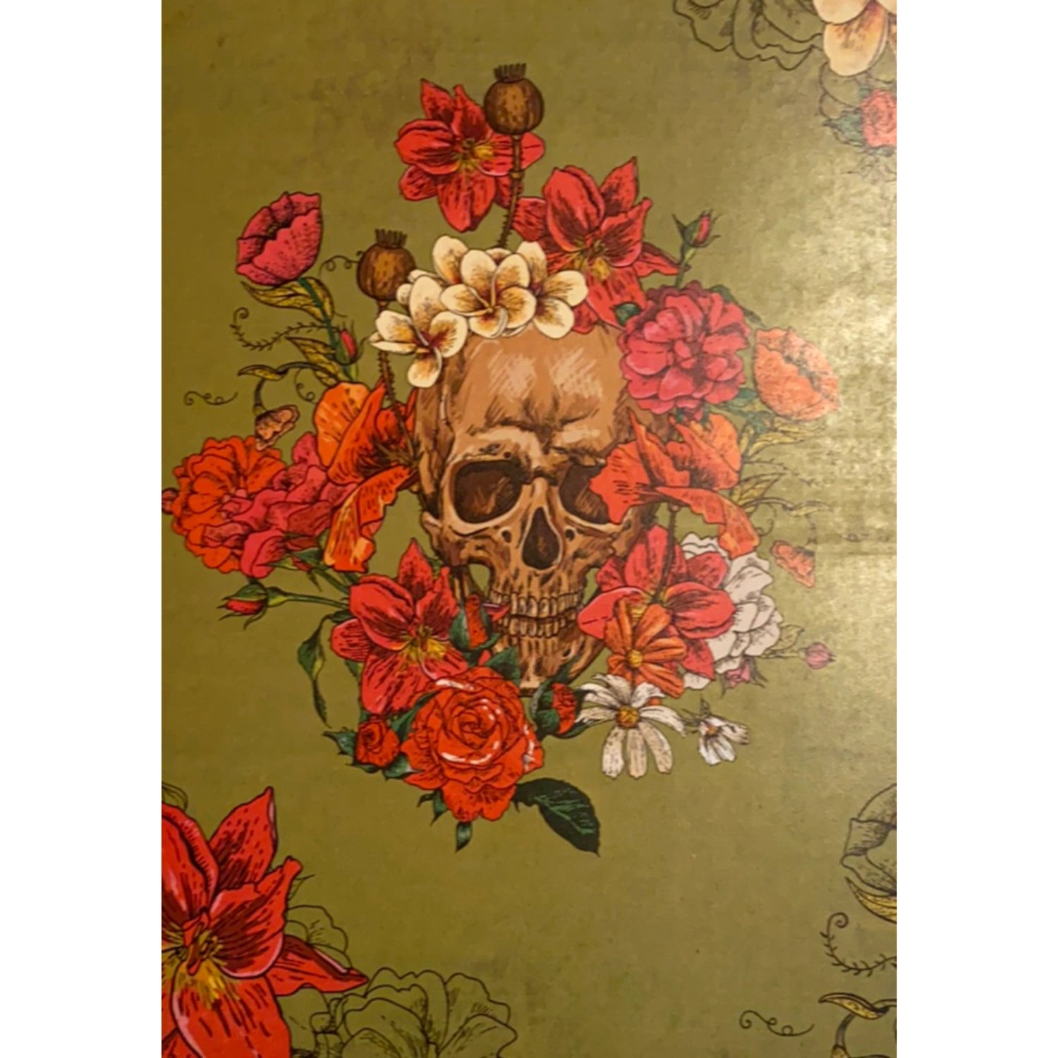 A human skull adorned with colorful flowers, including roses, poppies, and daisies, on a green background.