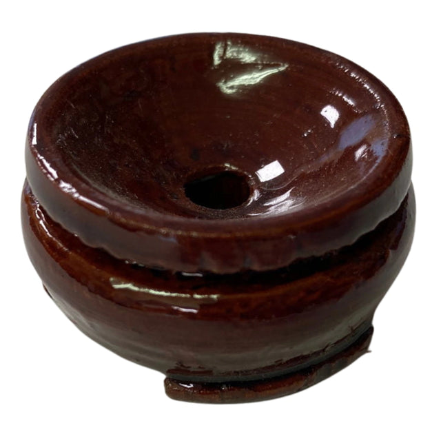 A small, brown ceramic incense burner with a hole in the center and a raised base.